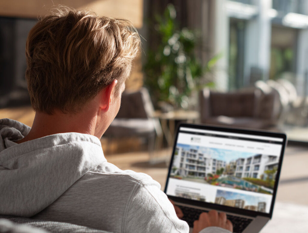 mann am laptop sieht sich immobilien an